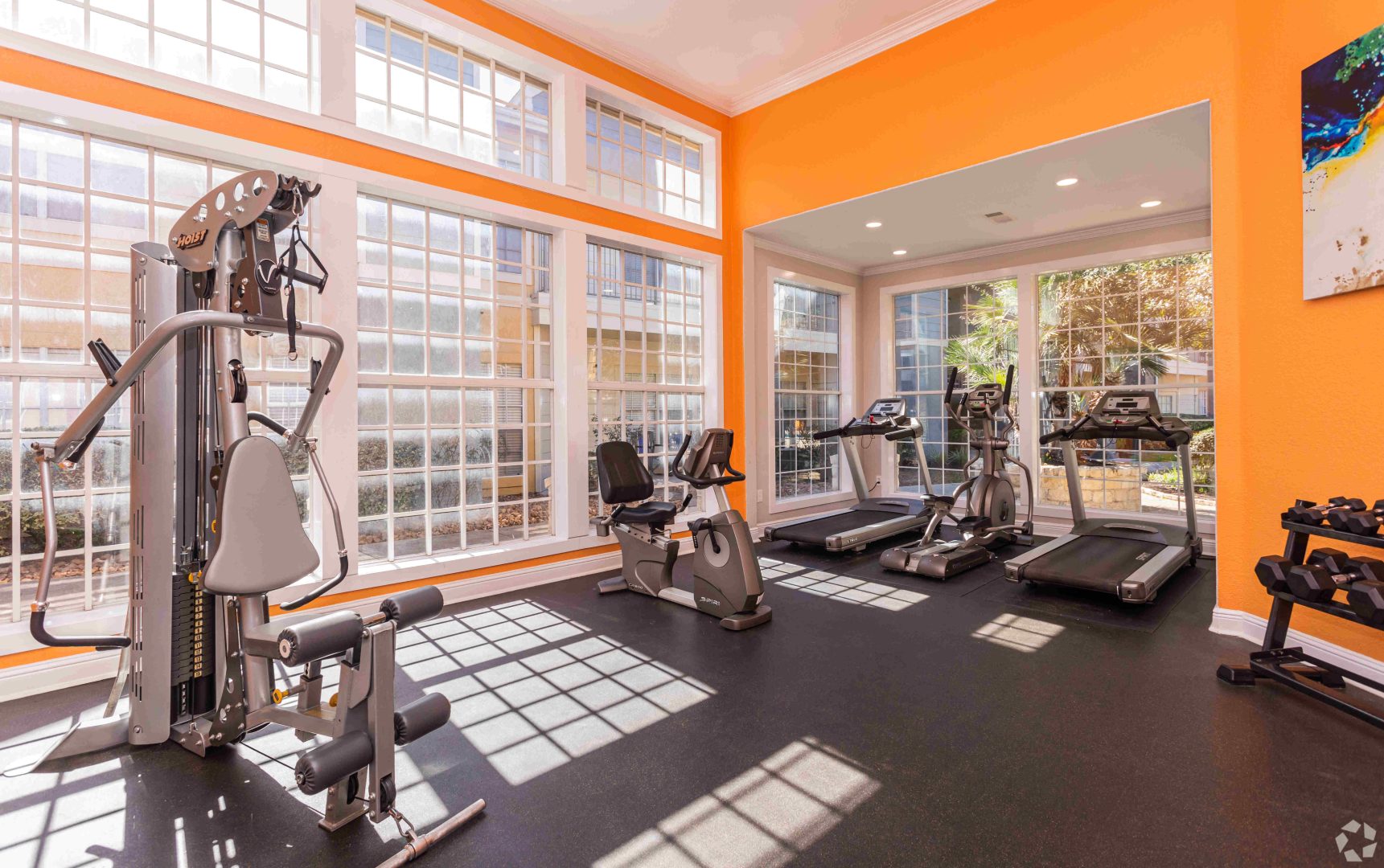 a gym room with orange walls and windows at The Westmount at Three Fountains